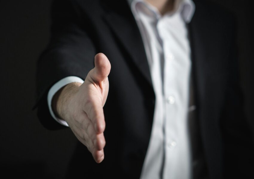 Close-up of a businessman extending hand for a handshake, symbolizing agreement and partnership.